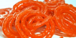 Orange jalebi sweets on a white surface.
