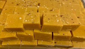 Yellow fudge squares with sprinkled nuts.