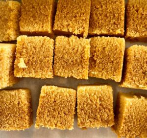 Golden cornbread squares arranged on parchment paper.