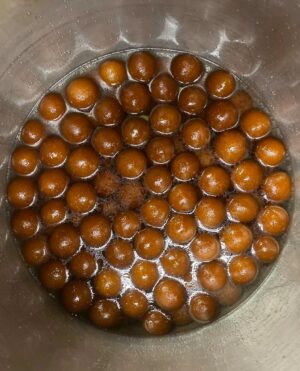 Gulab jamuns submerged in sugary syrup.