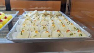 Tray of white pastries with pistachio garnish.
